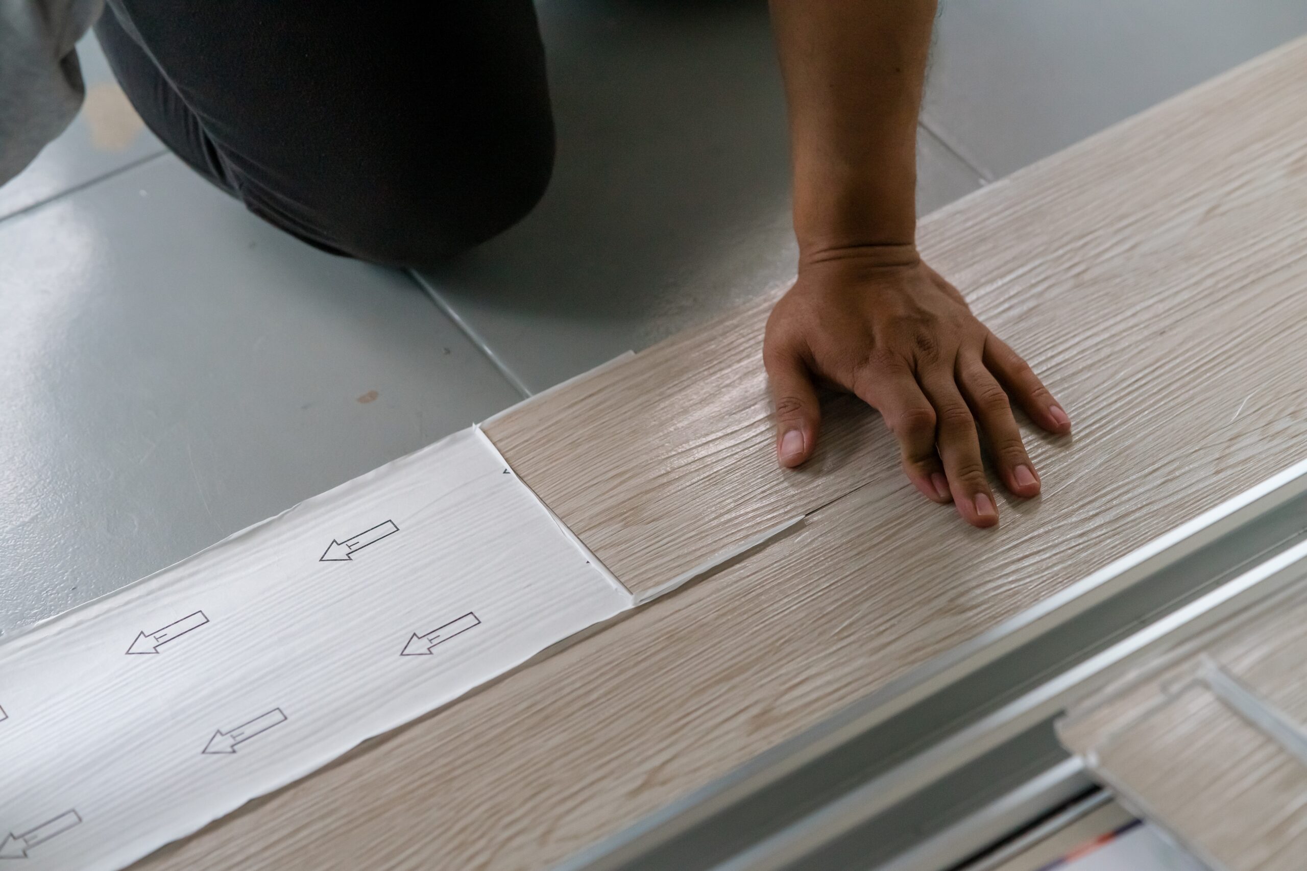 A person installing new vinyl tile floor, a DIY home project.