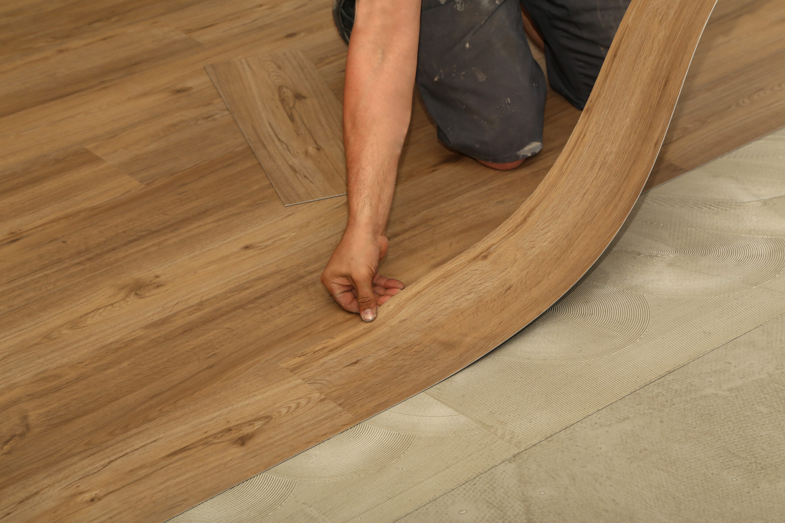 Worker installing new parquet vinyl tiles on floor